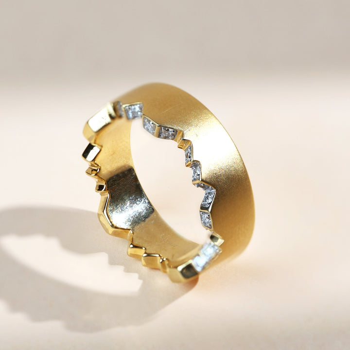 Angular side view of gold couple ring with inset diamonds along the irregular groove