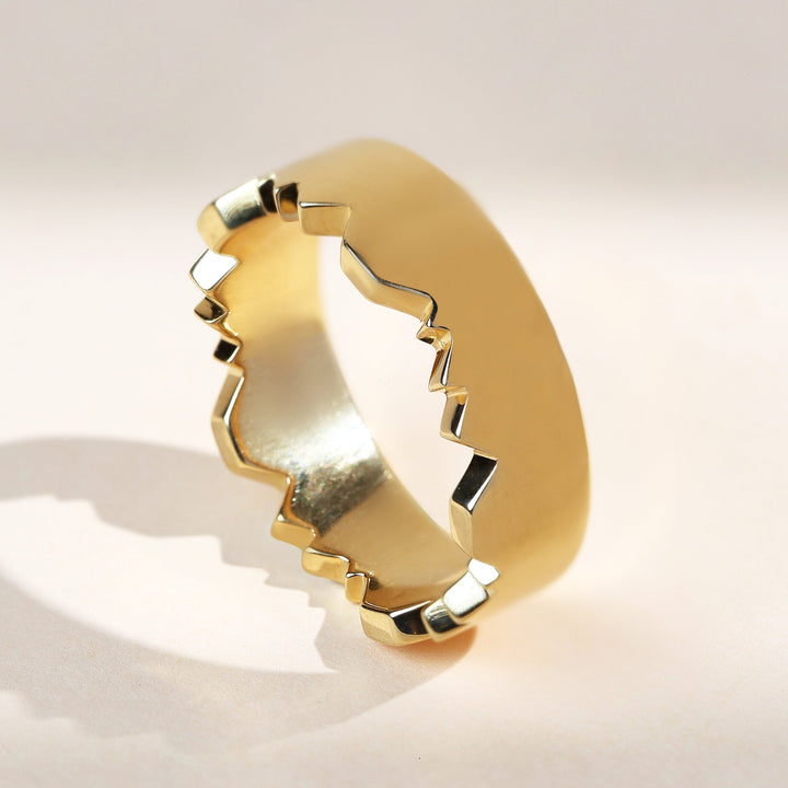 Gold matte finish couple ring with jagged inner design, angled view.