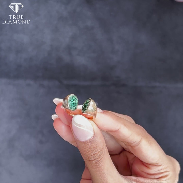 Woman wearing gold open ring with green gemstones