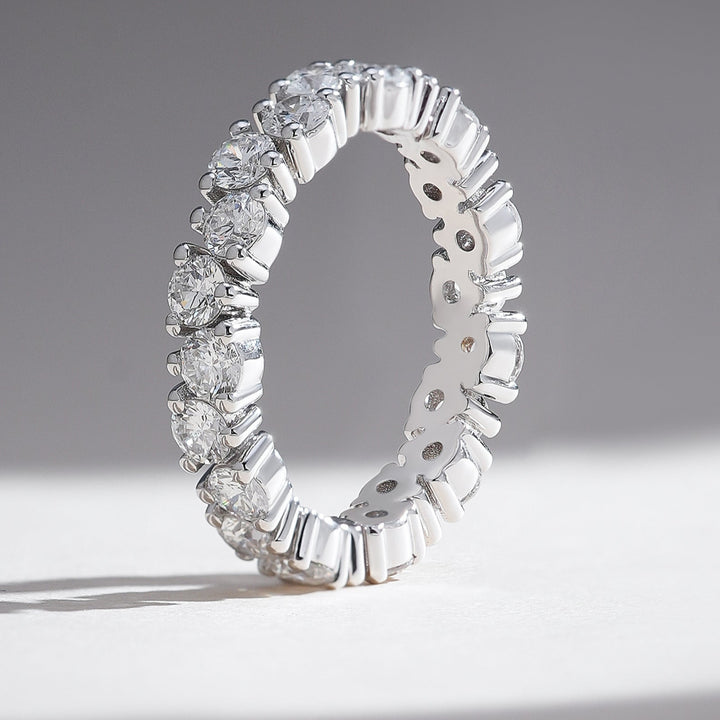 Standing profile of white gold round diamond eternity band with shared prong setting.