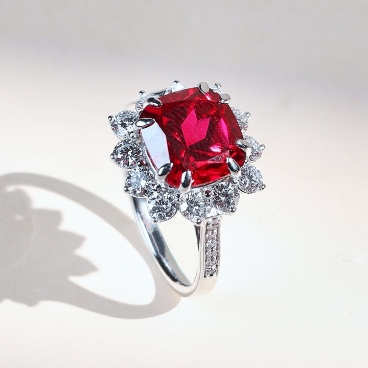 Ruby Embrace cocktail ring with cushion-cut red ruby surrounded by round diamonds in white gold
