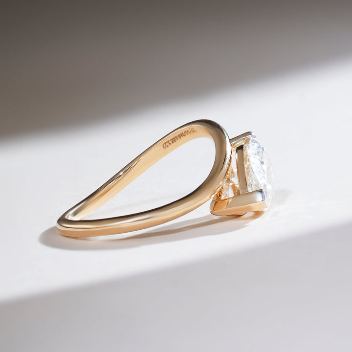 Side view of the Sirena 1.7 Ct pear solitaire ring showing the bypass band in polished yellow gold.