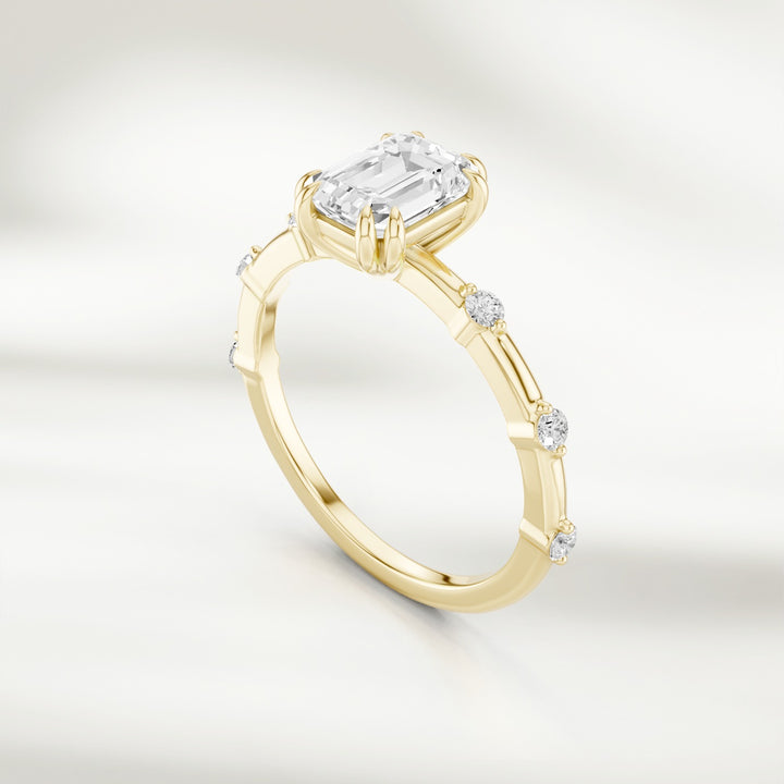 Angled view of 18K yellow gold band featuring a radiant emerald-cut diamond and round diamond stations.