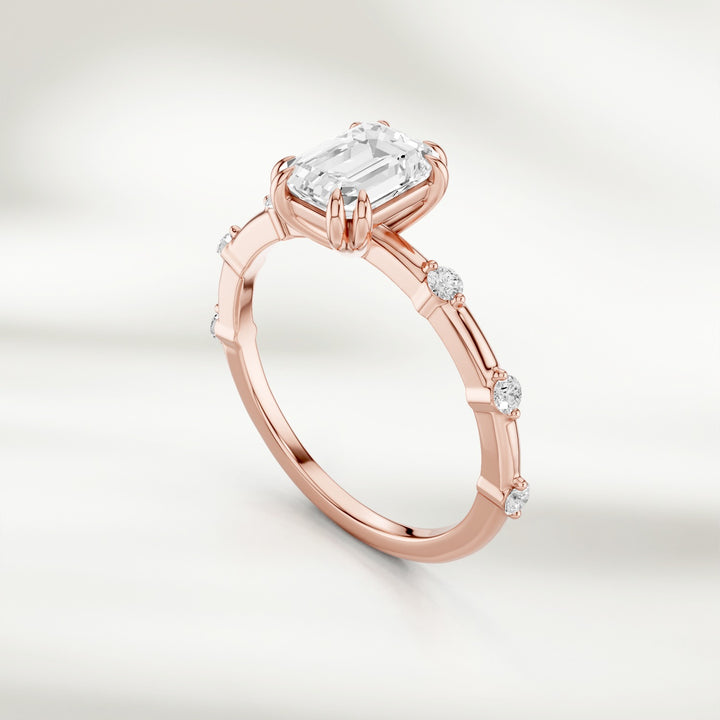 Angled view of 18K rose gold band featuring a radiant emerald-cut diamond and round diamond stations.