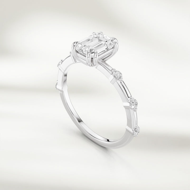 Angled view of 18K wg gold band featuring a radiant emerald-cut diamond and round diamond stations.