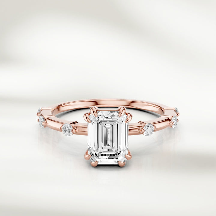 18K rose gold solitaire ring with an emerald-cut diamond centerpiece and evenly spaced round diamond accents along the band.