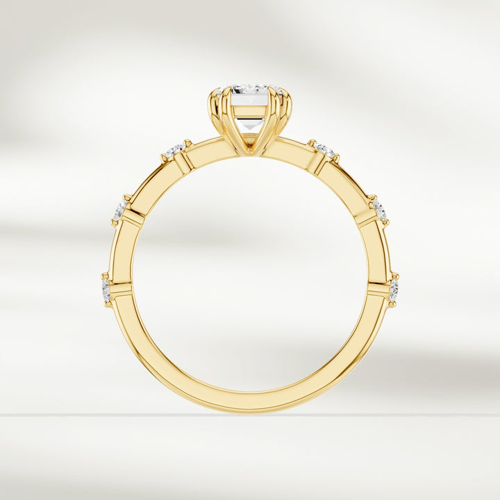 Top-down view of 18K yellow gold solitaire ring with emerald-cut diamond and round brilliant accents.