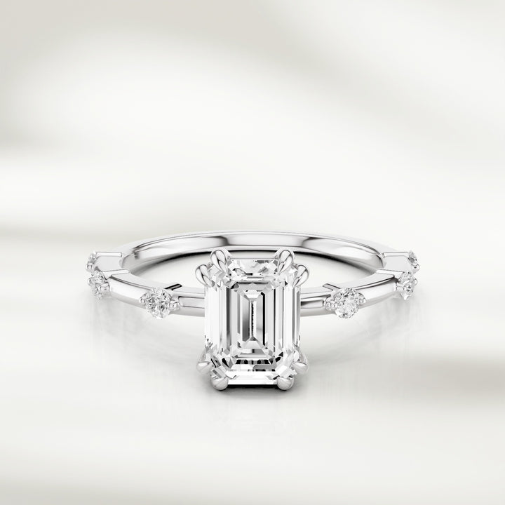 18K White gold solitaire ring with an emerald-cut diamond centerpiece and evenly spaced round diamond accents along the band.