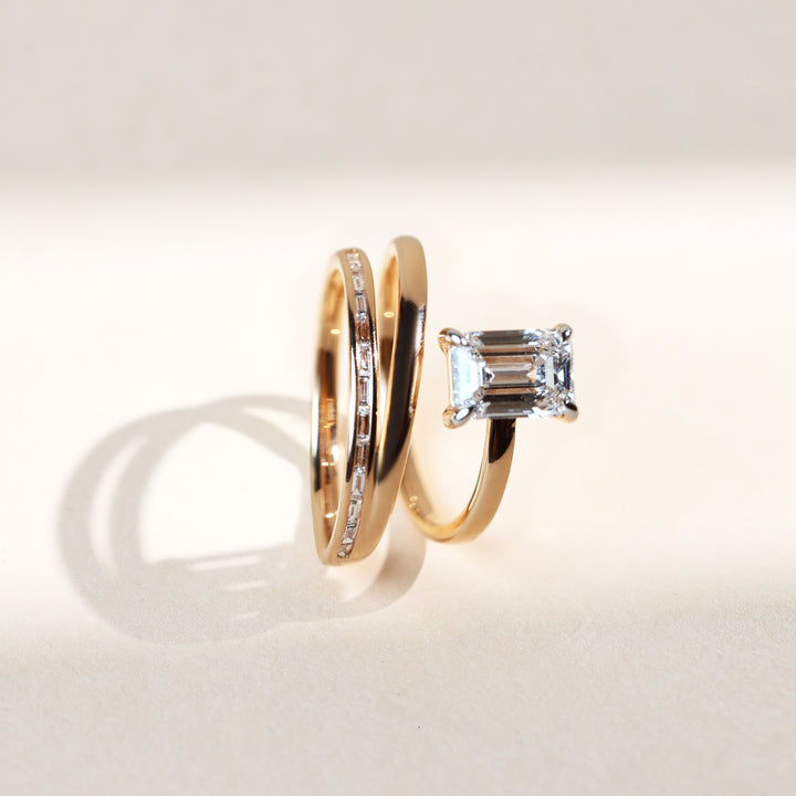 Gold cocktail ring with emerald-cut diamond solitaire and dual band view from the front.