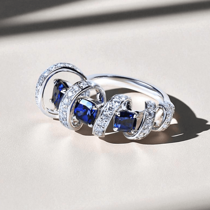 Close-up of Star Weave Cocktail Ring with sapphire center and diamond spiral design.
