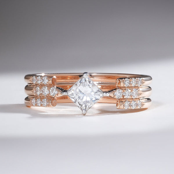 Rose gold triple-band ring with a central princess-cut diamond and pavé-set side diamonds for a modern, architectural look.