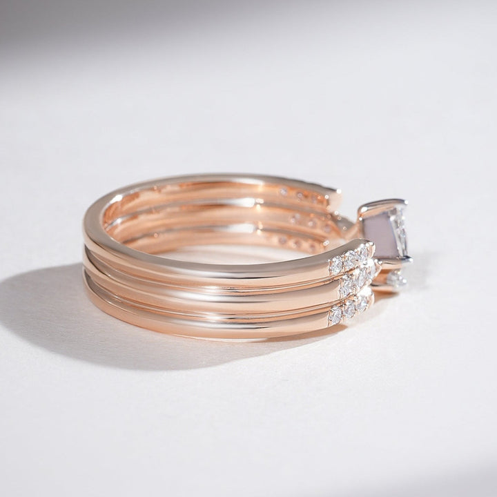 Side view of rose gold triple-band ring featuring a princess-cut diamond centerpiece and pavé detailing.